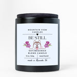 Candle with 'Be Still' label featuring a dog illustration on a white background