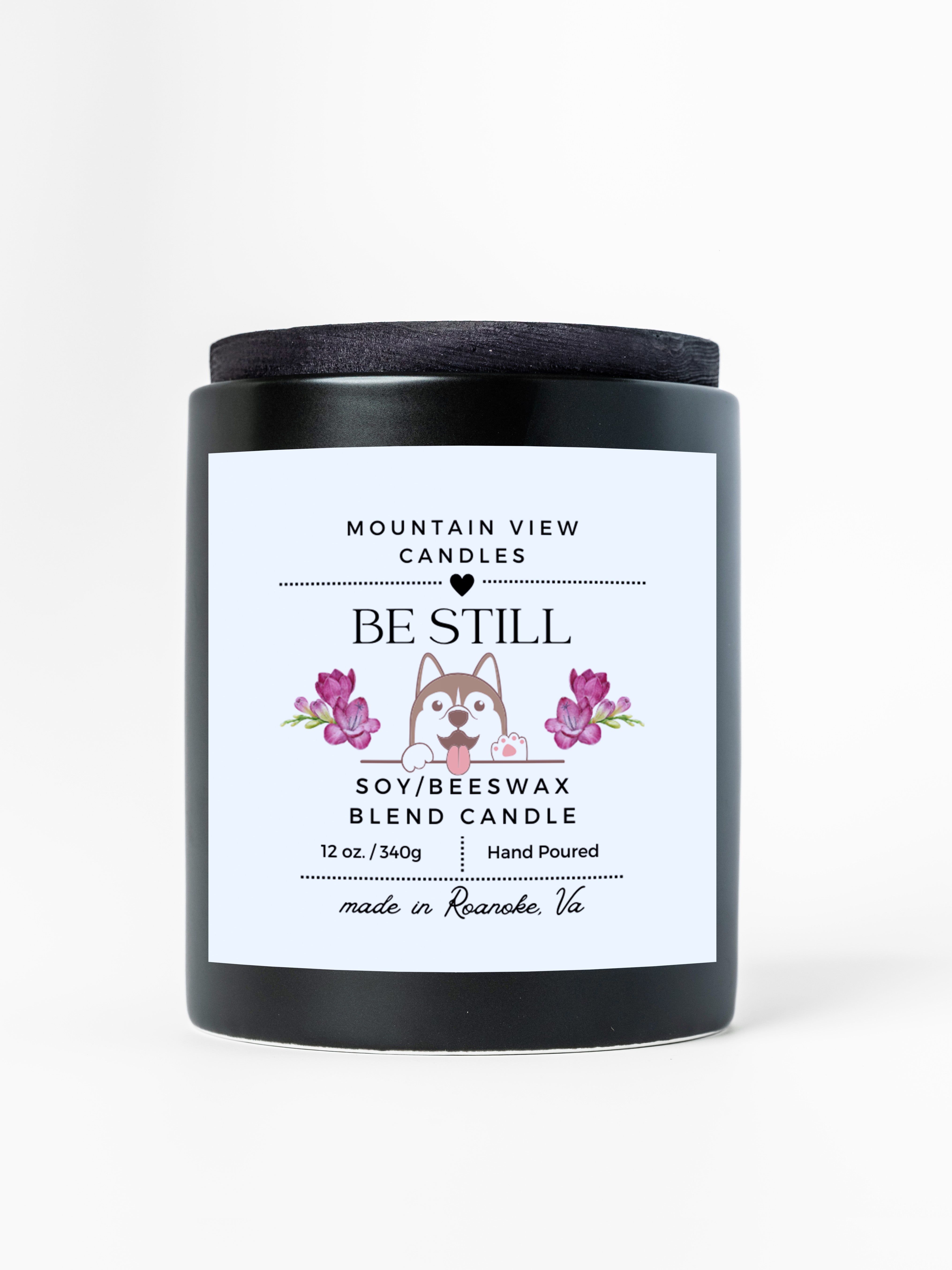 Candle with 'Be Still' label featuring a dog illustration on a white background
