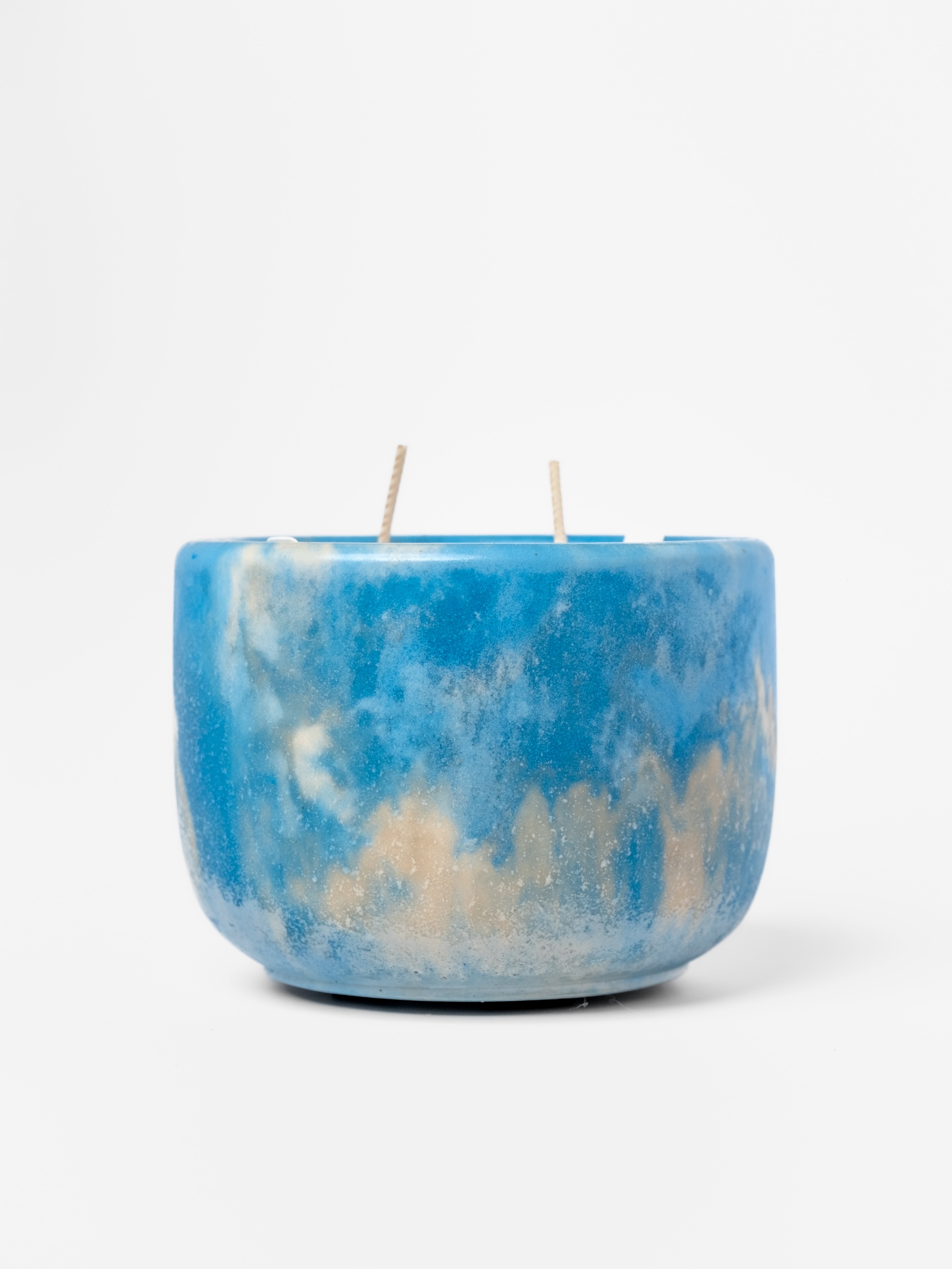 Blue and beige marbled candle on a white background