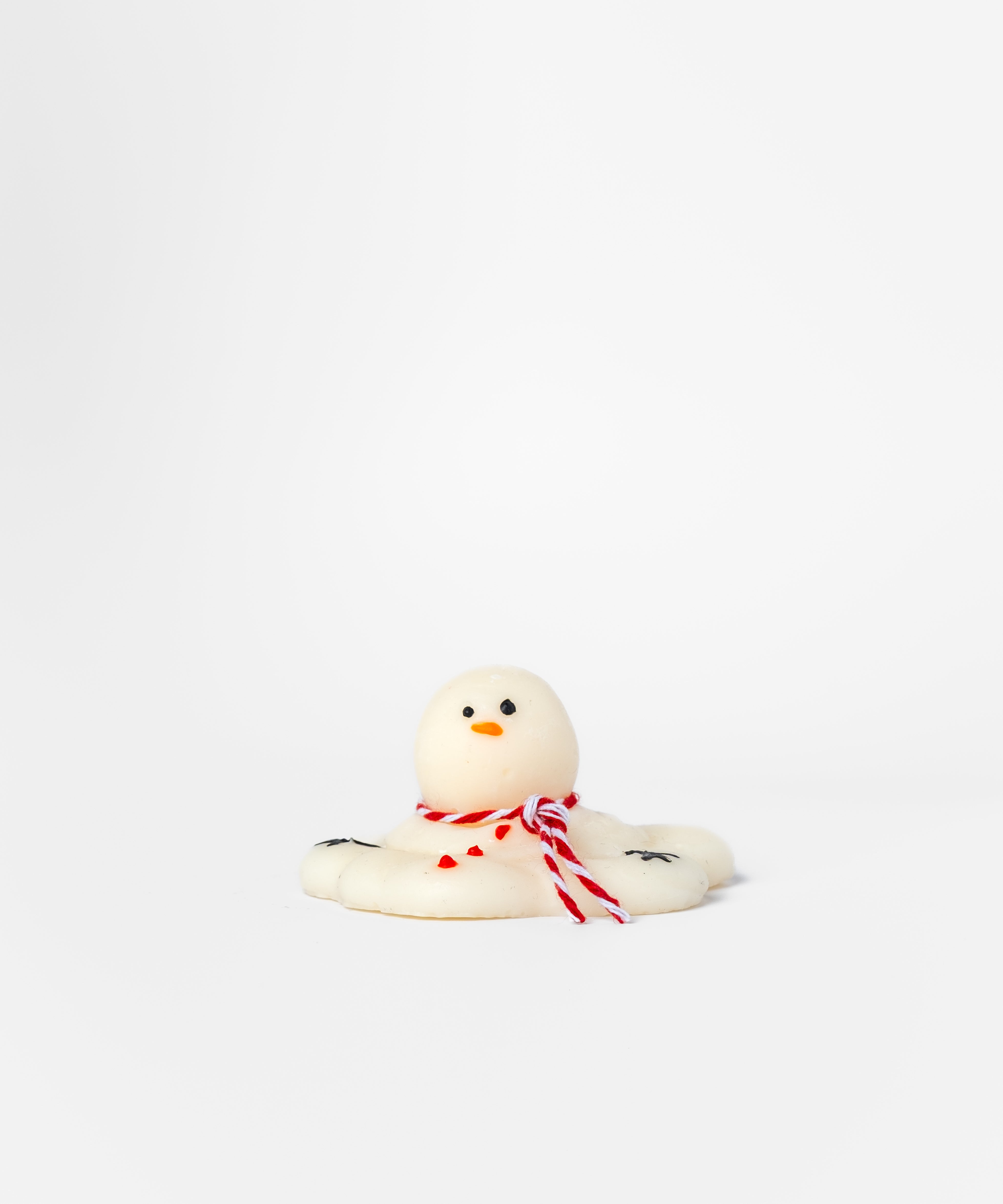 Small white snowman wax melt with a red bow on a white background