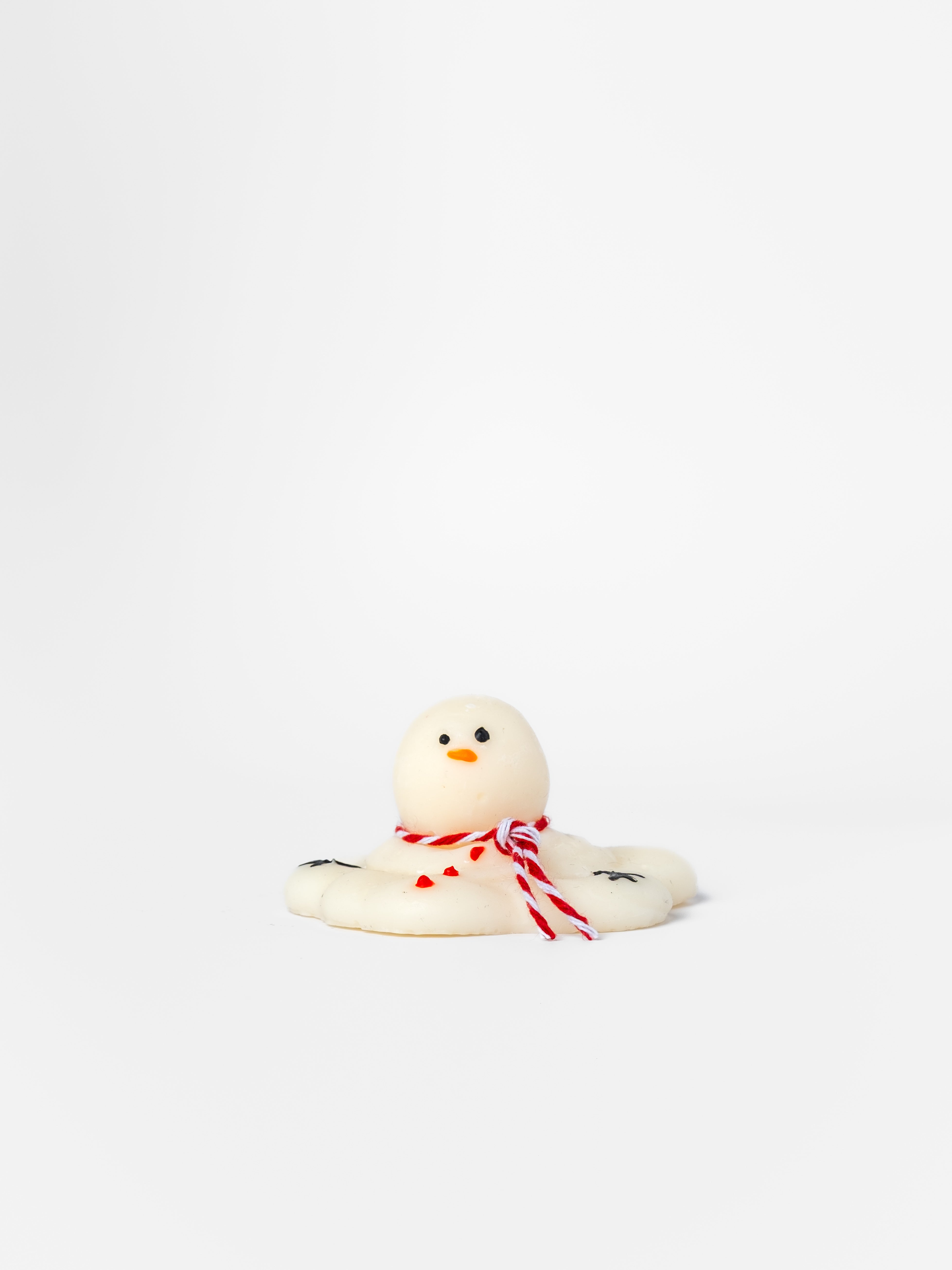Small white snowman wax melt with a red bow on a white background