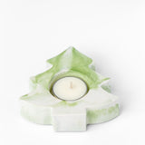 Green and white tree-shaped candle holder with a lit candle on a white background