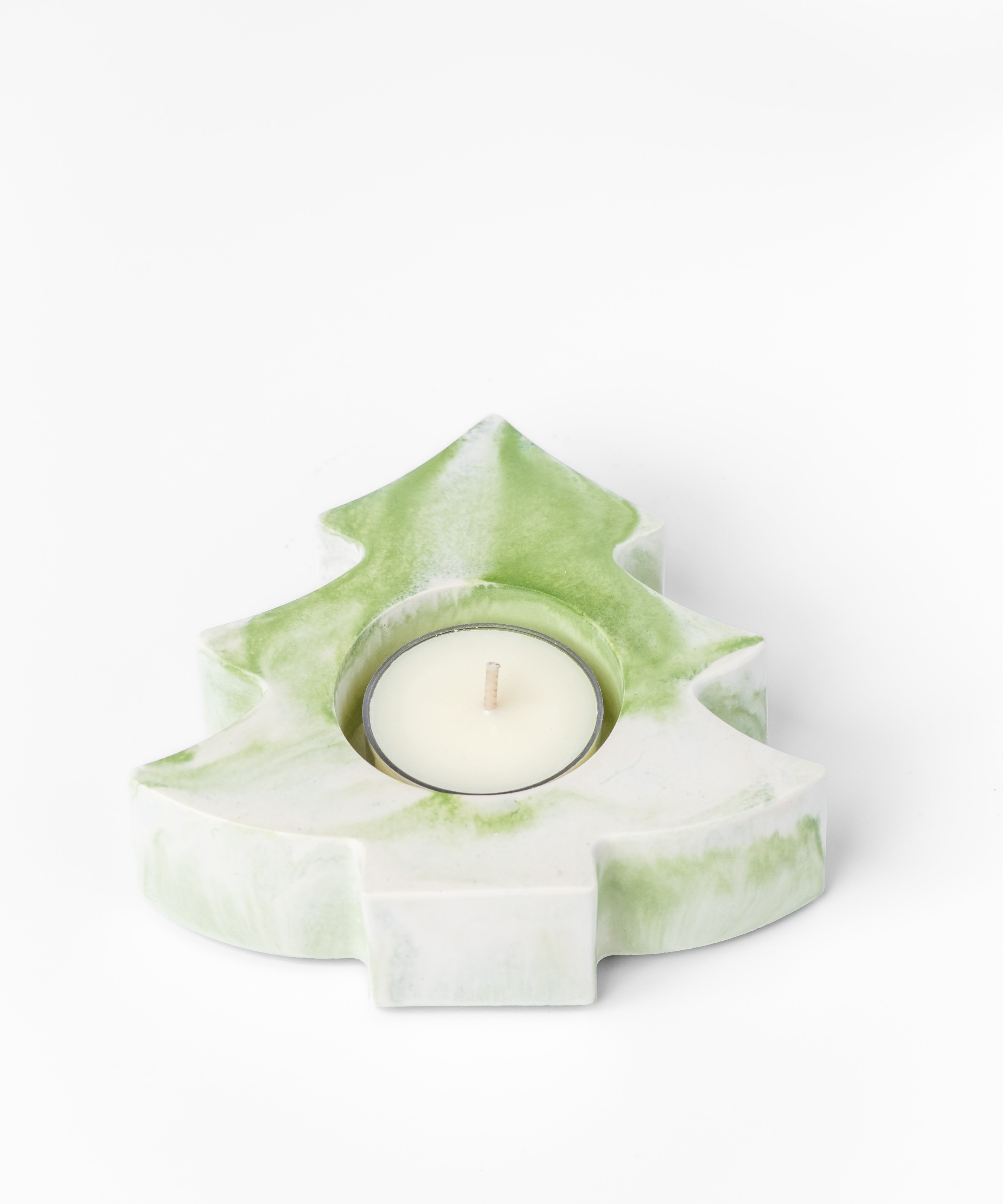 Green and white tree-shaped candle holder with a lit candle on a white background