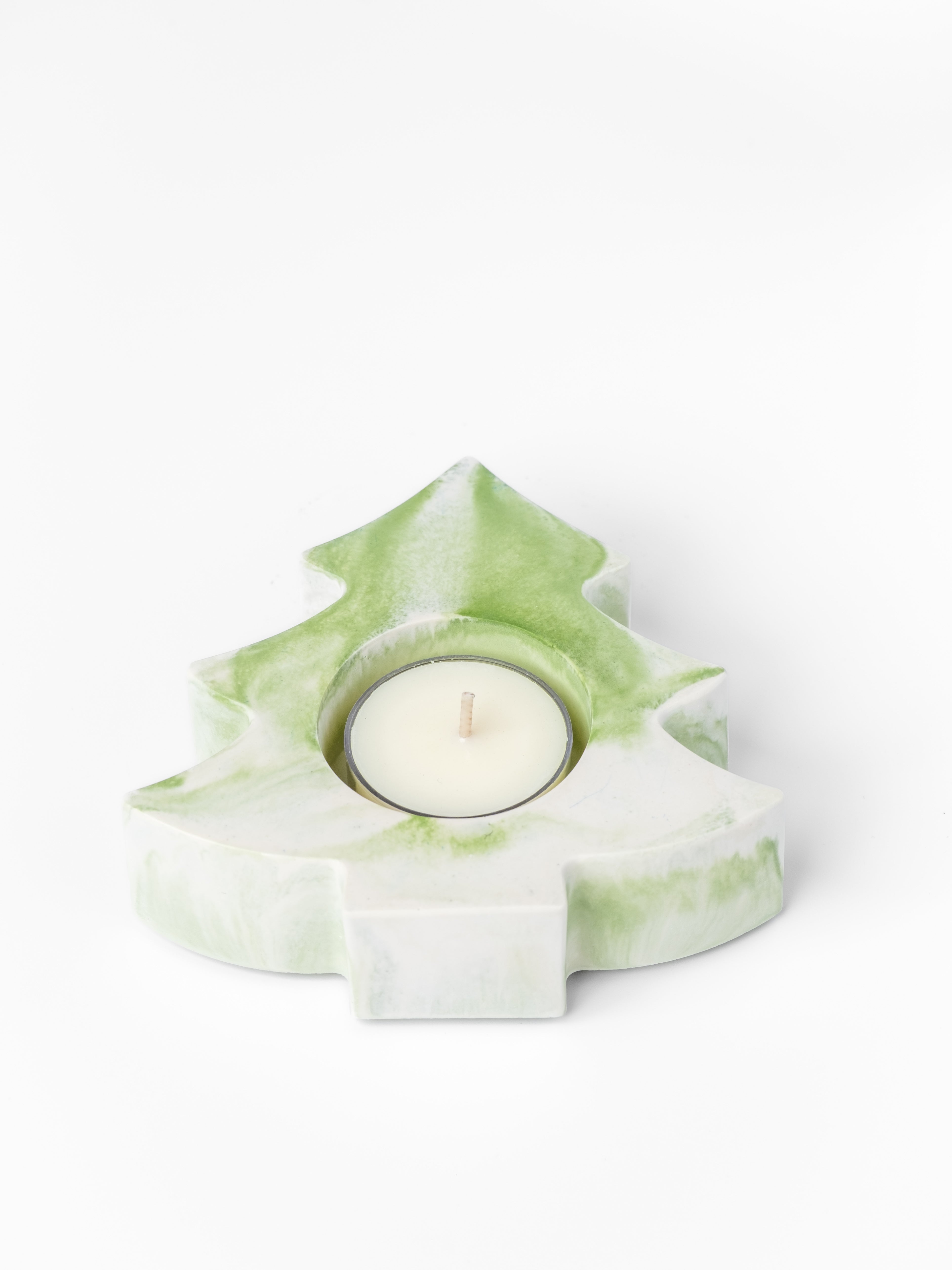 Green and white tree-shaped candle holder with a lit candle on a white background