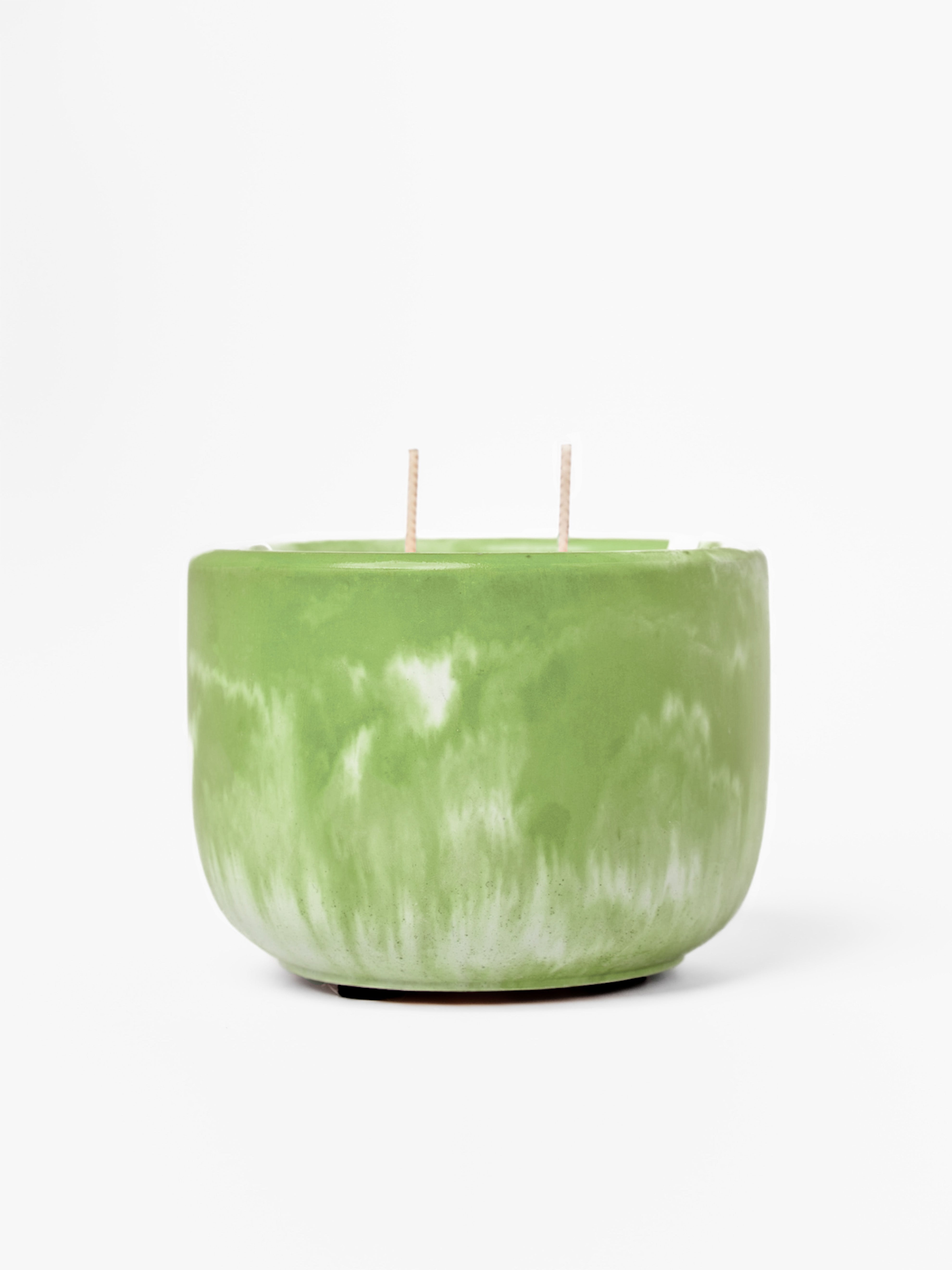 Green marbled candle with two wicks on a white background