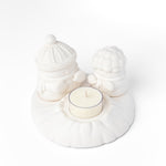 White ceramic holder with a small candle on a white background