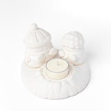 White ceramic holder with a small candle on a white background