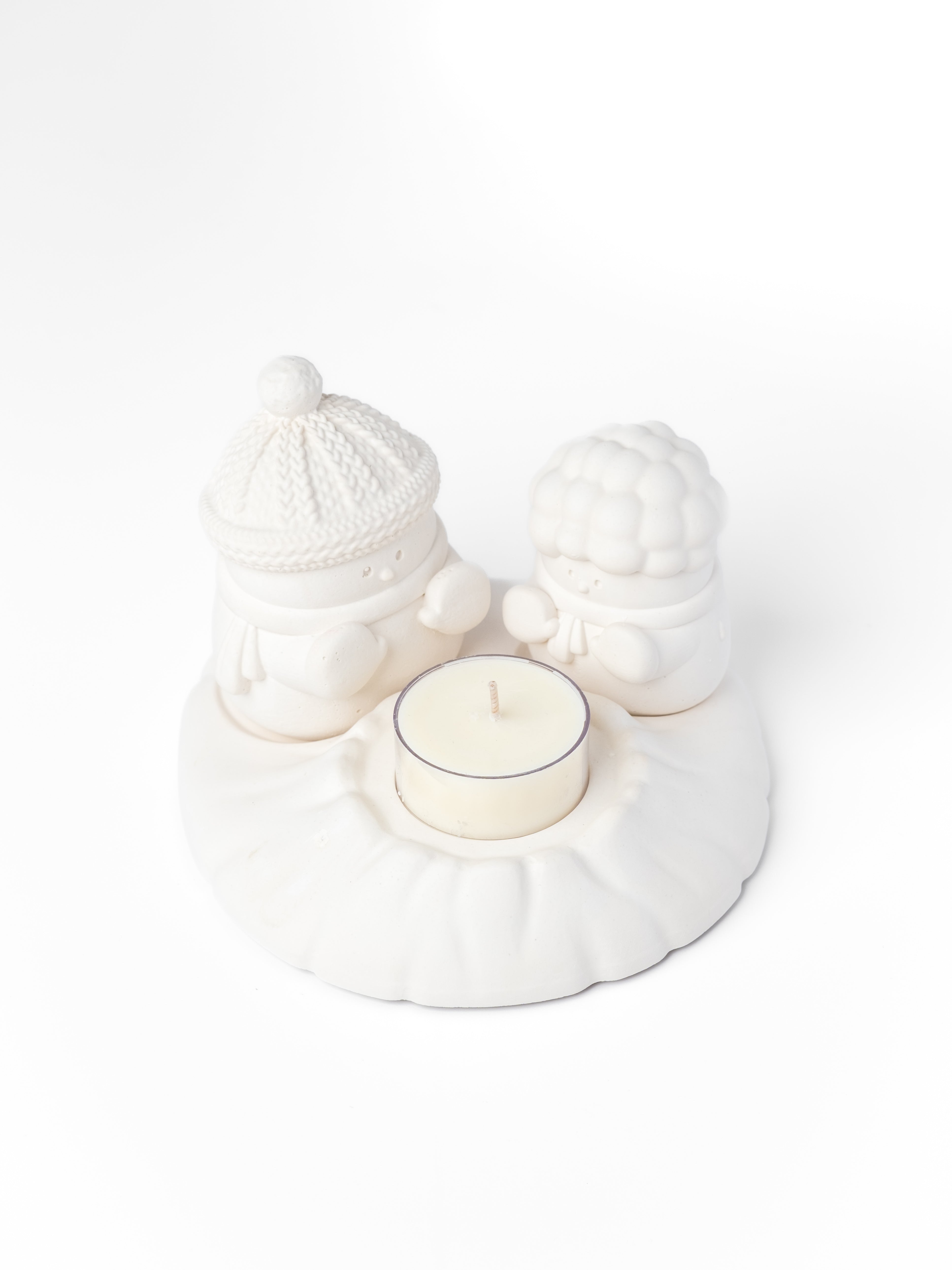 White ceramic holder with a small candle on a white background