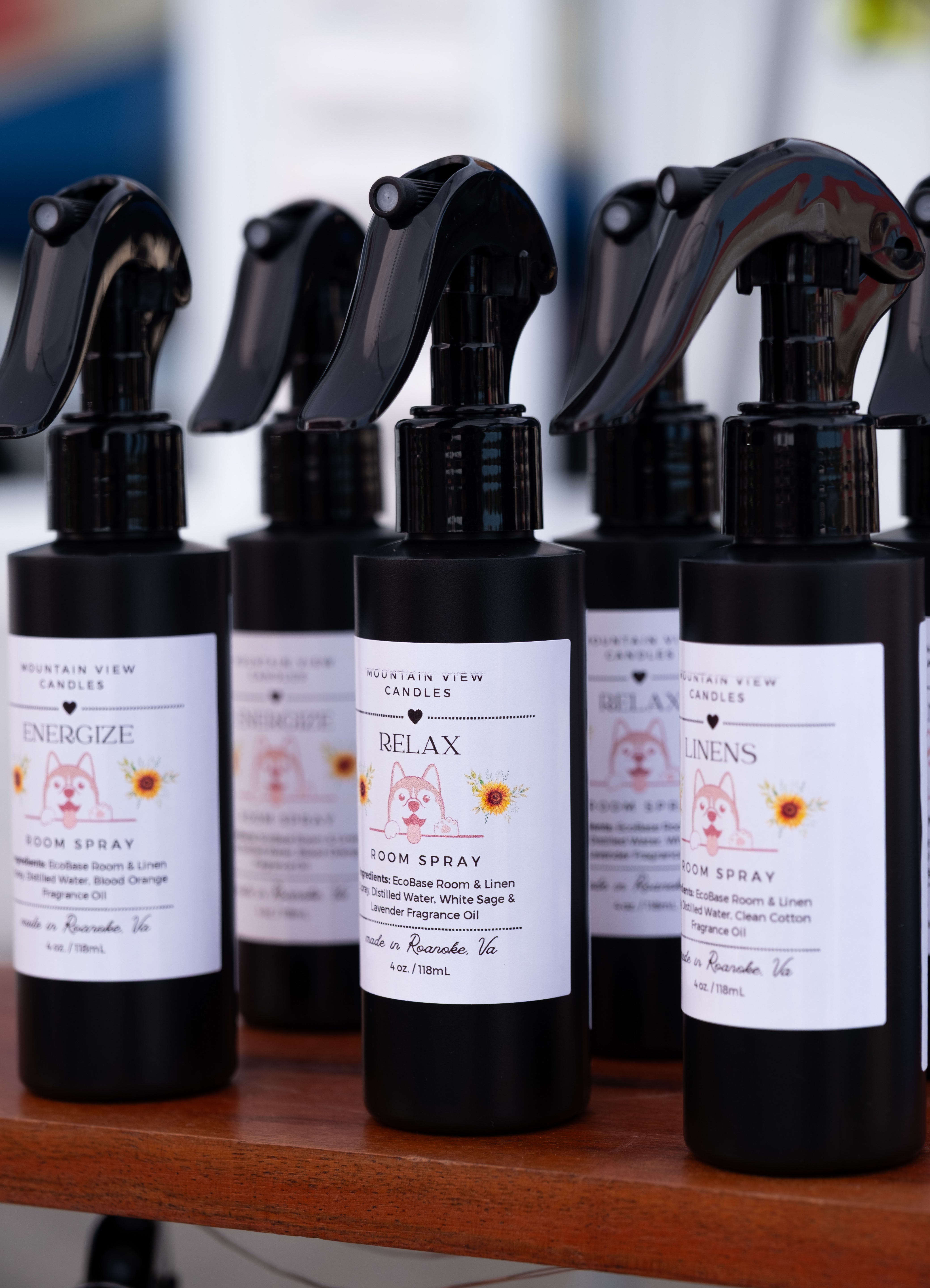 Row of black spray bottles with labels on a wooden surface