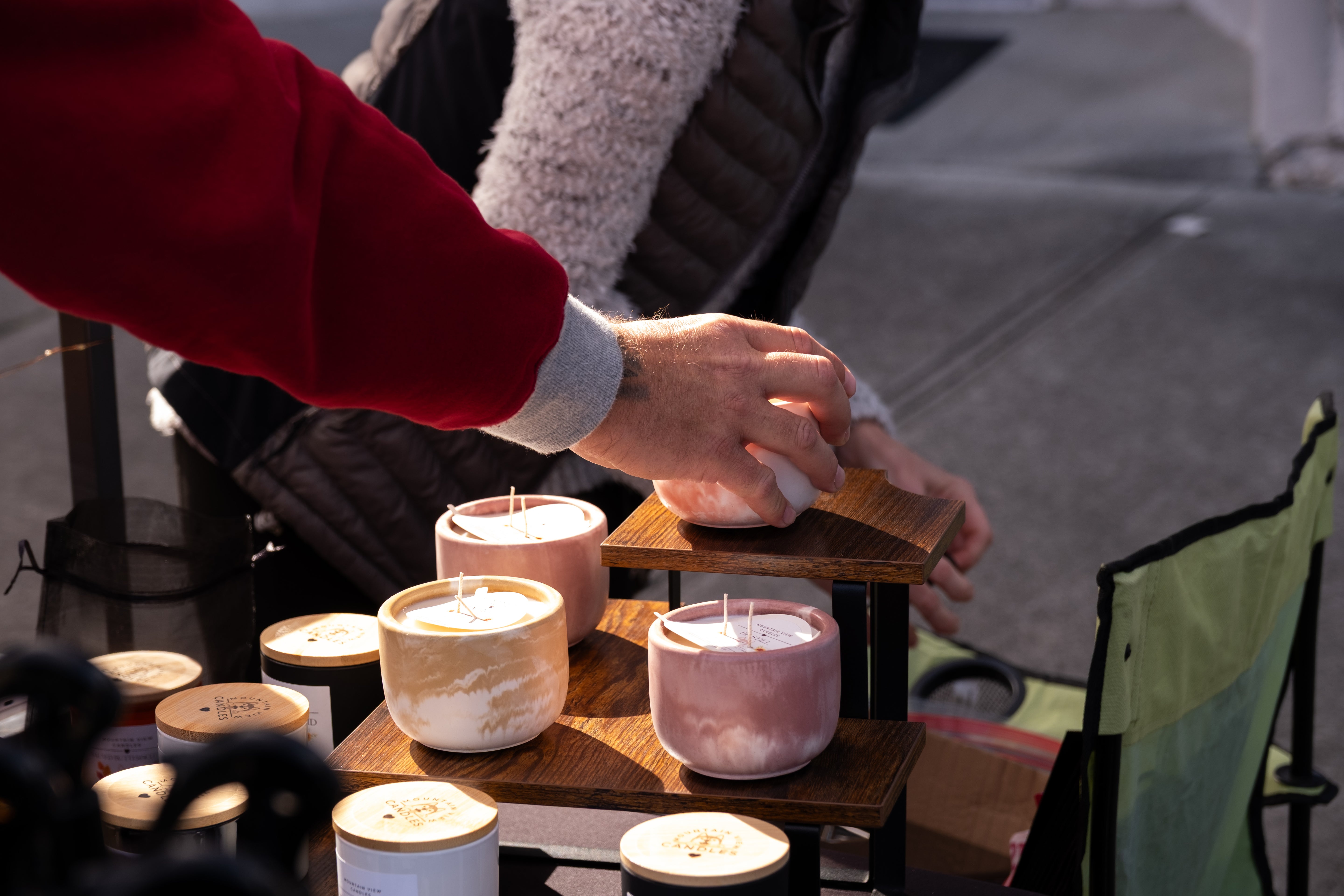Two hands holding a small object with a blurred background of shelves with containers.