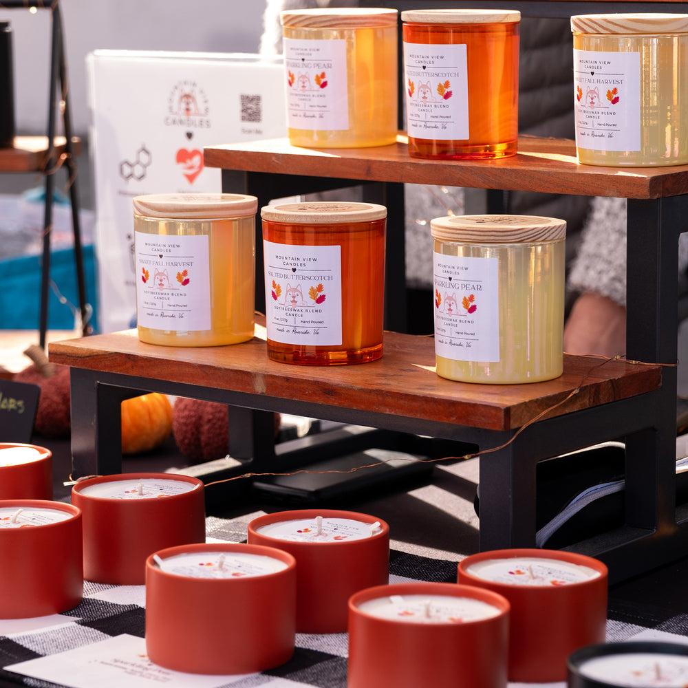 Candles displayed on a wooden shelf with visible labels.