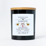 Black candle with a wooden lid and 'Namaste' label on a white background