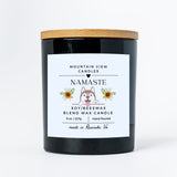 Black candle with a wooden lid and 'Namaste' label on a white background