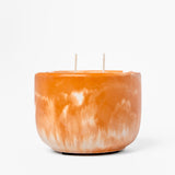 Orange marbled candle with two wicks on a white background