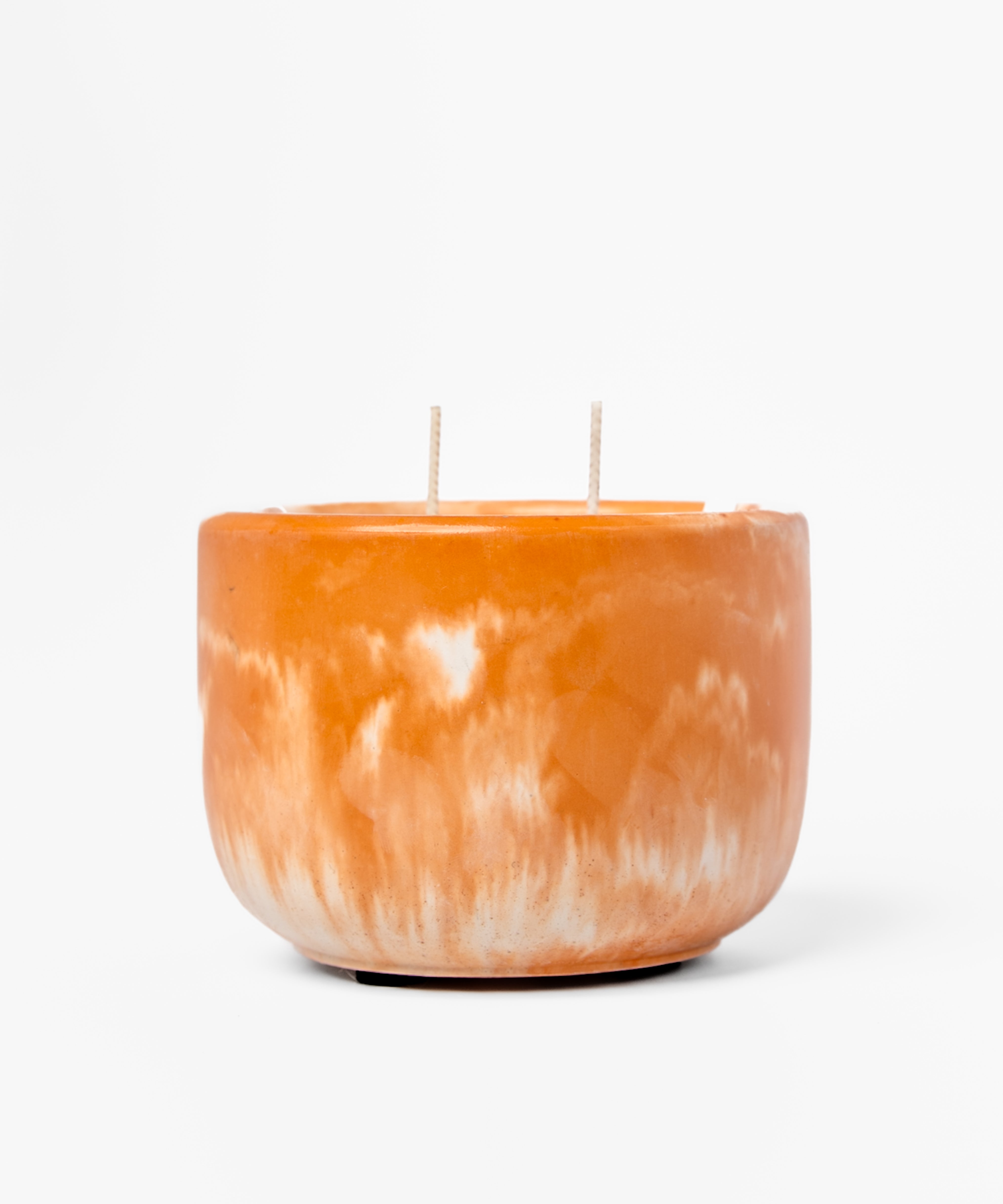 Orange marbled candle with two wicks on a white background