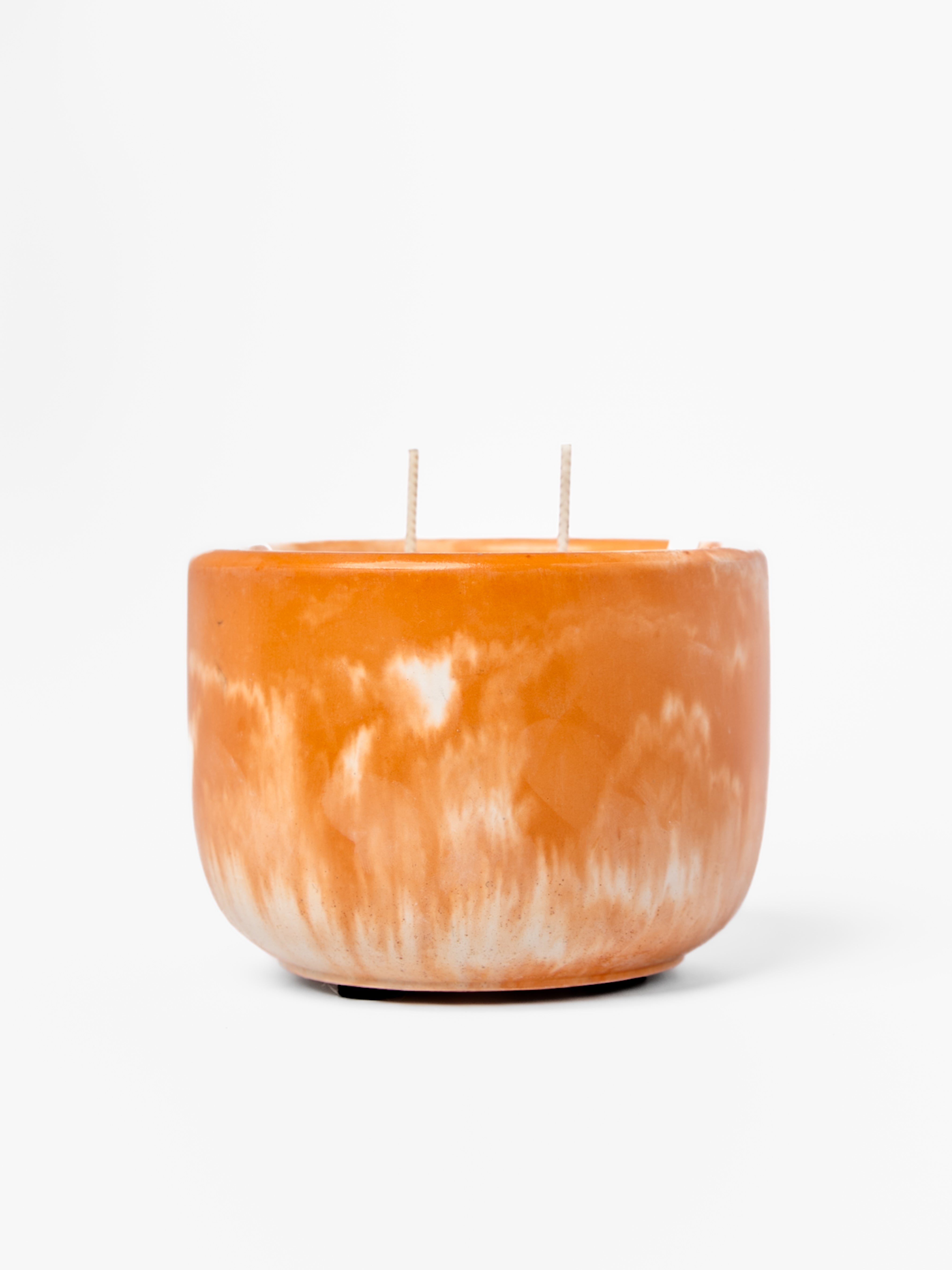 Orange marbled candle with two wicks on a white background